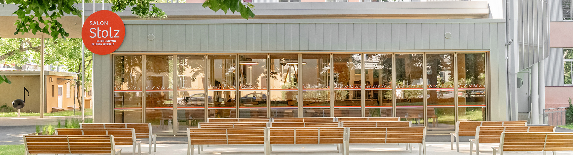 KIMUS Graz GmbH_SalonStolz Außenansicht des Salon Stolz, Glasfassade, Außenbereich mit Sitzbänken