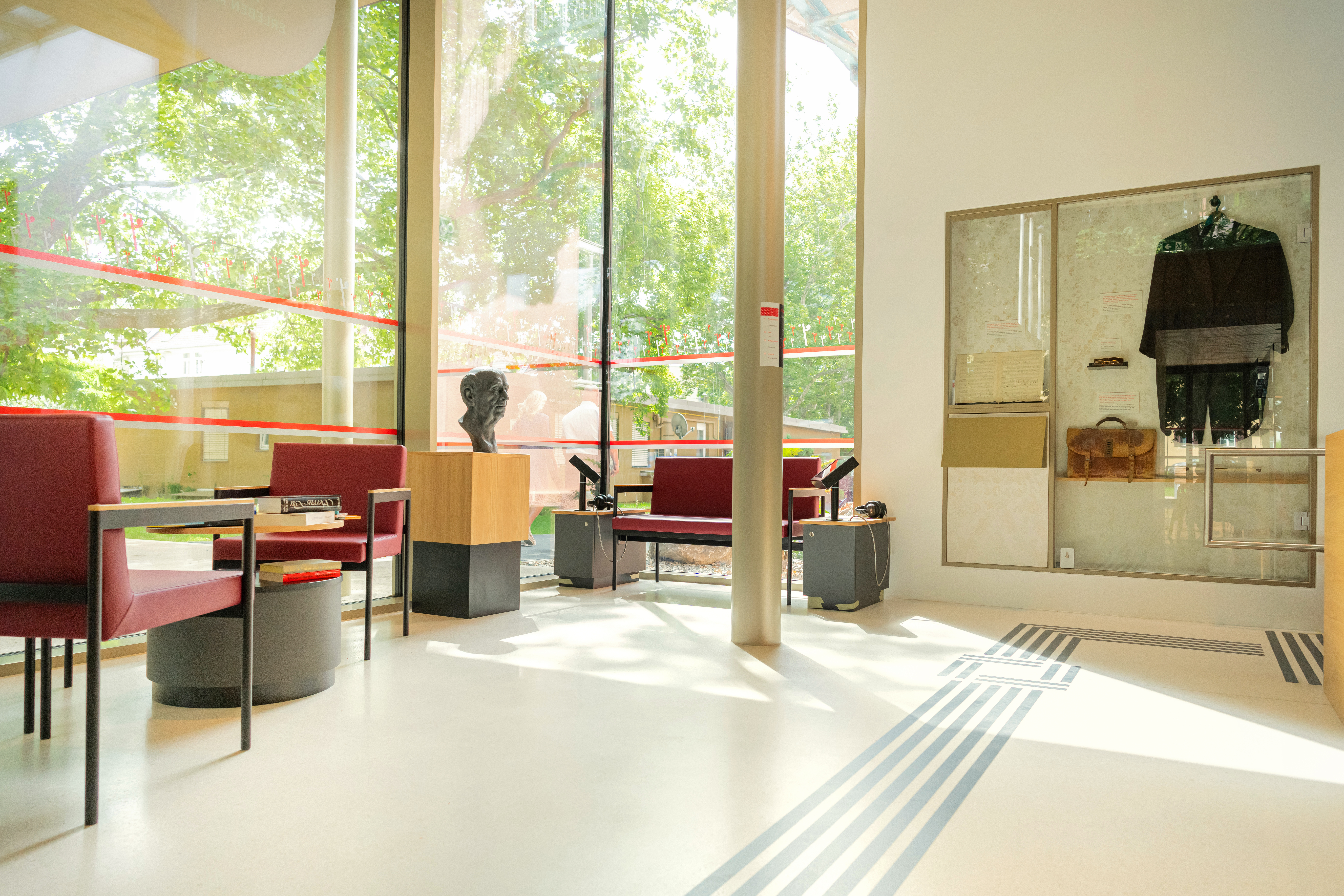 Architekturfoto des Innenraums. Stühle und Bänke, eine Büste von Robert Stolz.