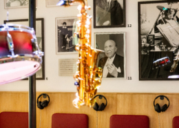 Nahaufnahme aus der Lebensbühne. Im Vordergrund hängt ein Saxophon, im Hintergrund hängen Fotografien von Robert Stolz an der Wand.